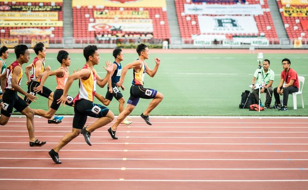 How do different track surfaces affect the performance of runners in 100-meter sprints?